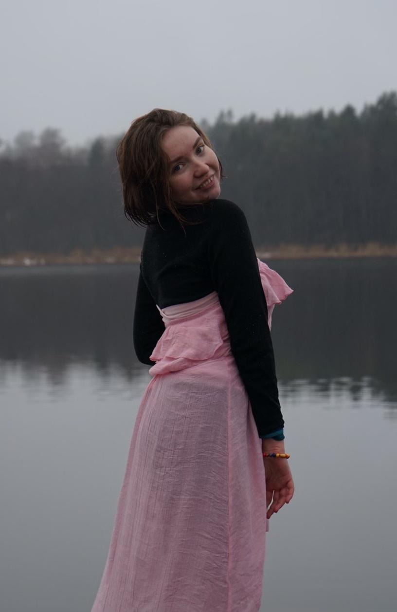 En bild på en tjej i en rosa klänning som ler mot kameran