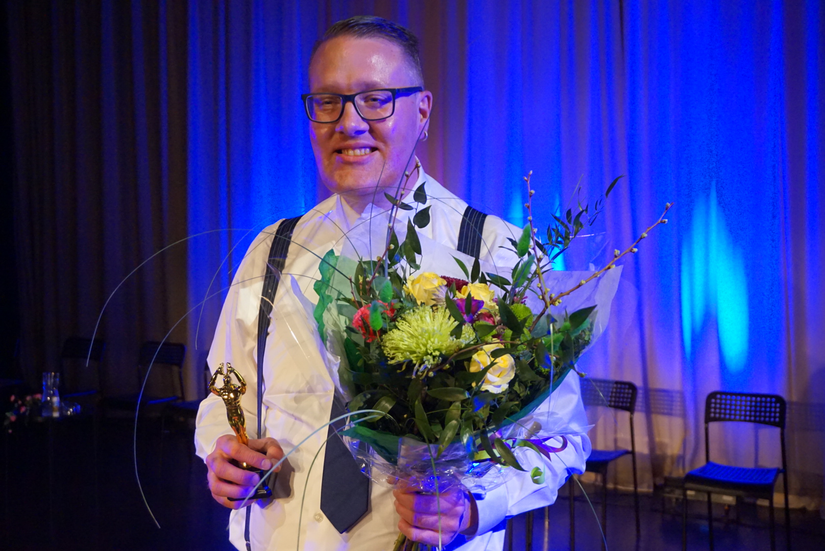 En bild på vinnaren Robban som håller i blommor och en pokal