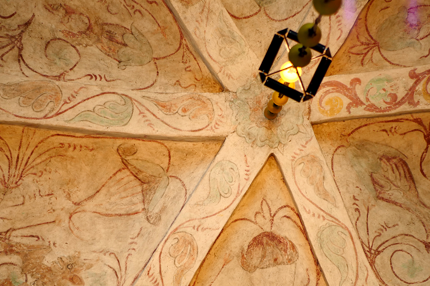 interiören i Håbo-Tibble kyrka där väggar och tak är täckta av medeltida kalkmålningar