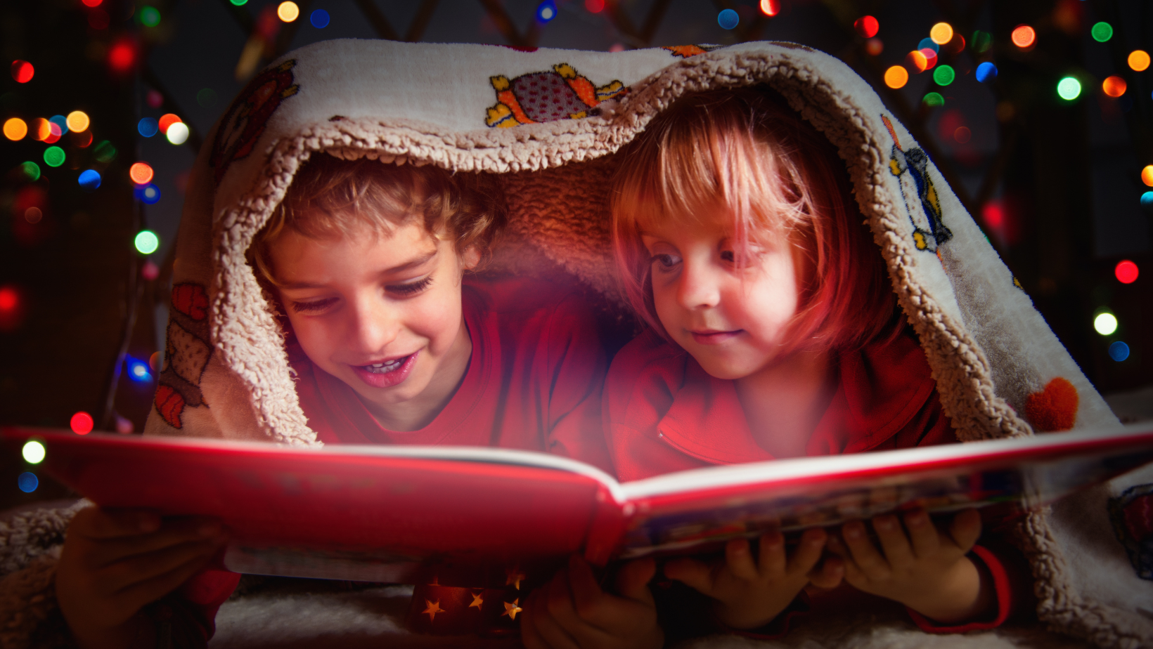 Två barn som läser en bok under en filt. Magisk belysning i bakgrunden.