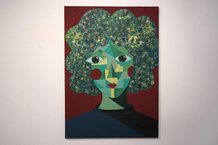 Målning som föreställer att kubistiskt ansikte med ett stort blommigt hår mot roströd botten
