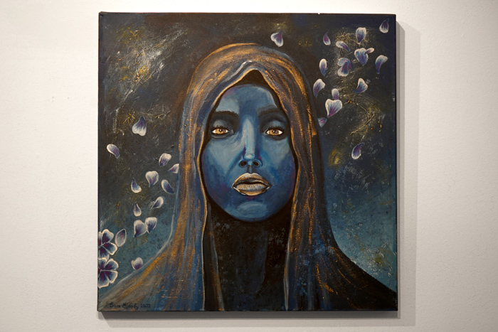 En målning i  blå färger föreställande en kvinna med slöja som tittar på betraktaren