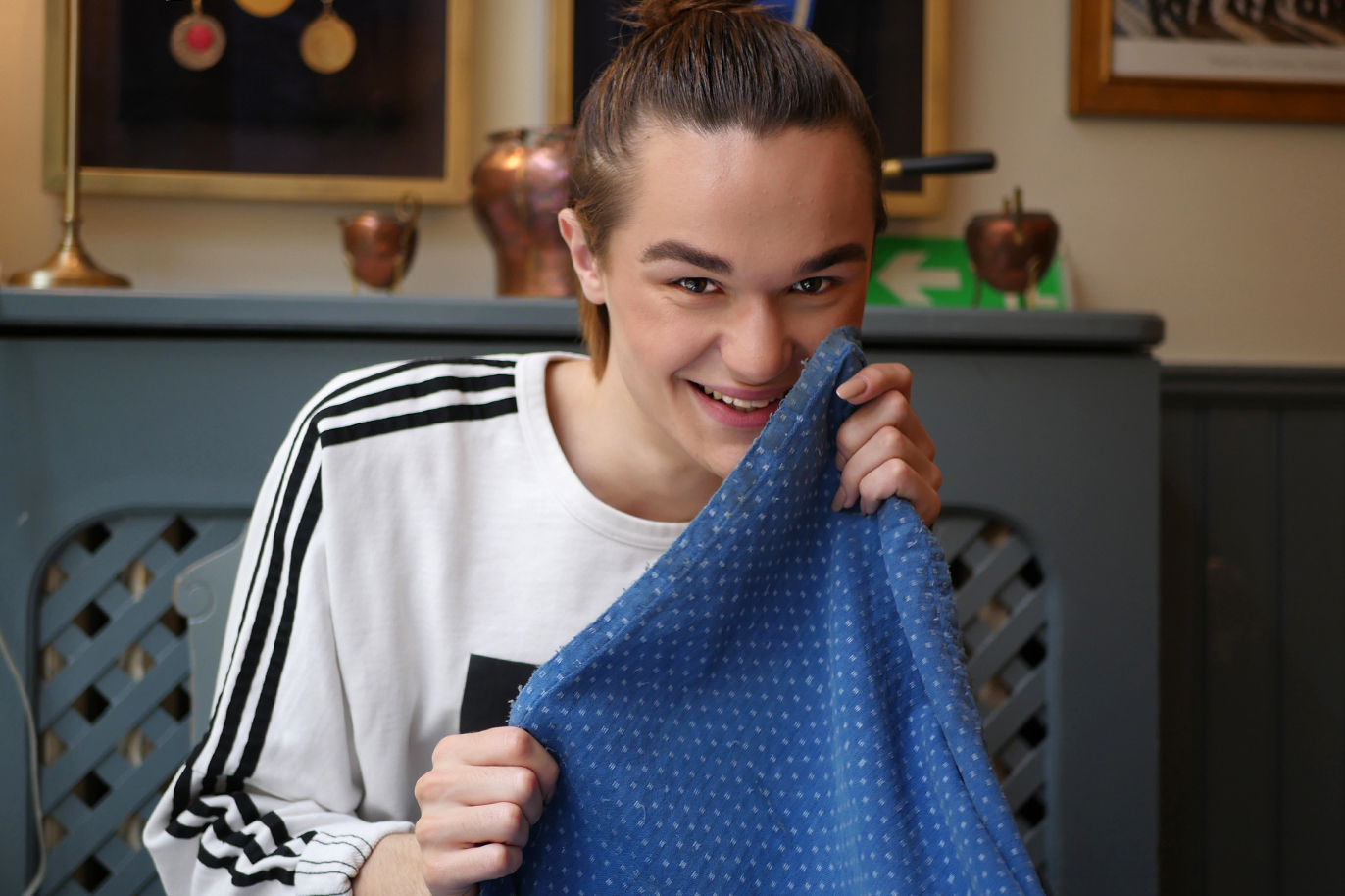 Youtubern Thomas Sekelius i svartvit Adidaströja håller upp en blå duk och skrattar.
