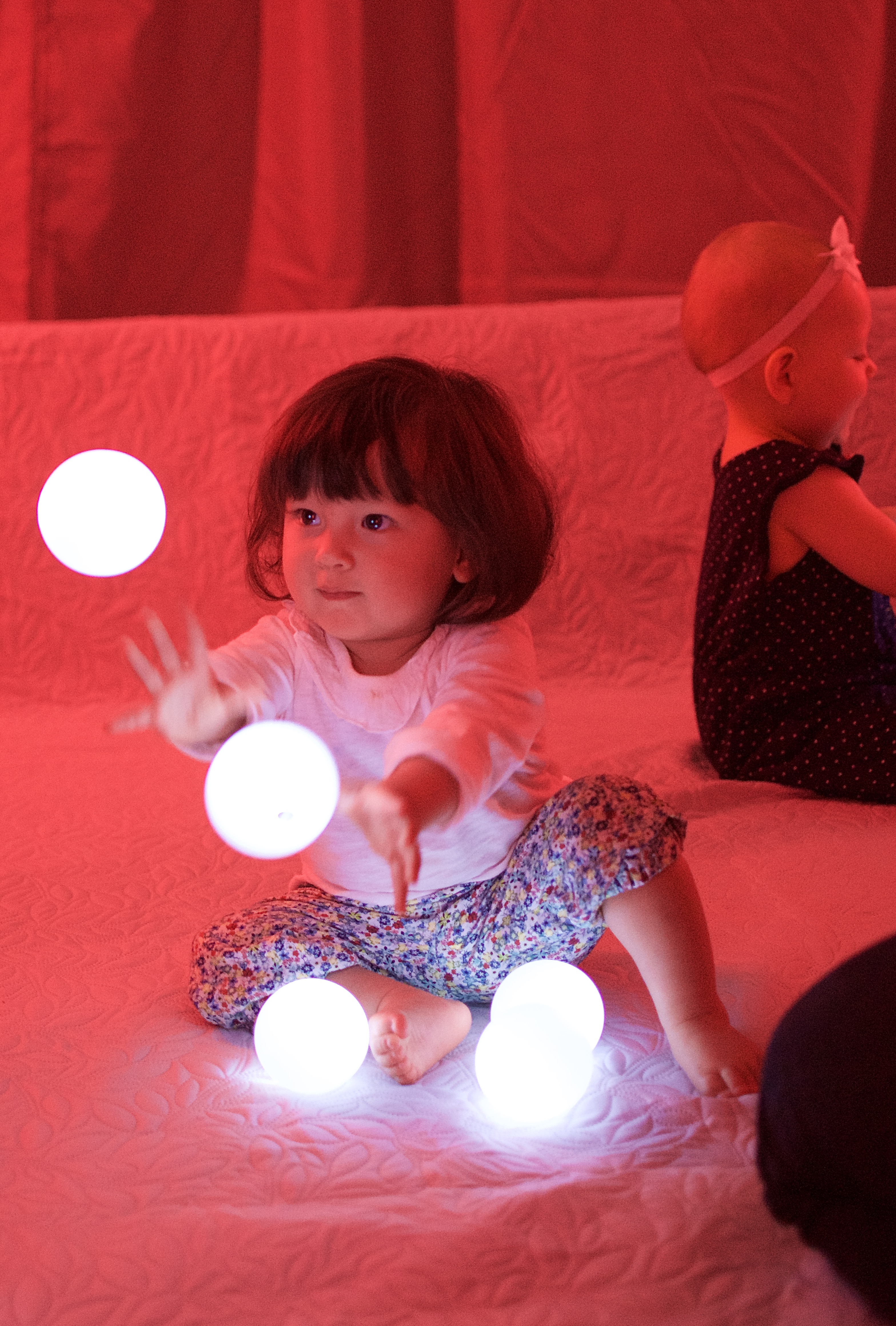 Rött ljus. Ett litet barn som sitter och leker med självlysande bollar