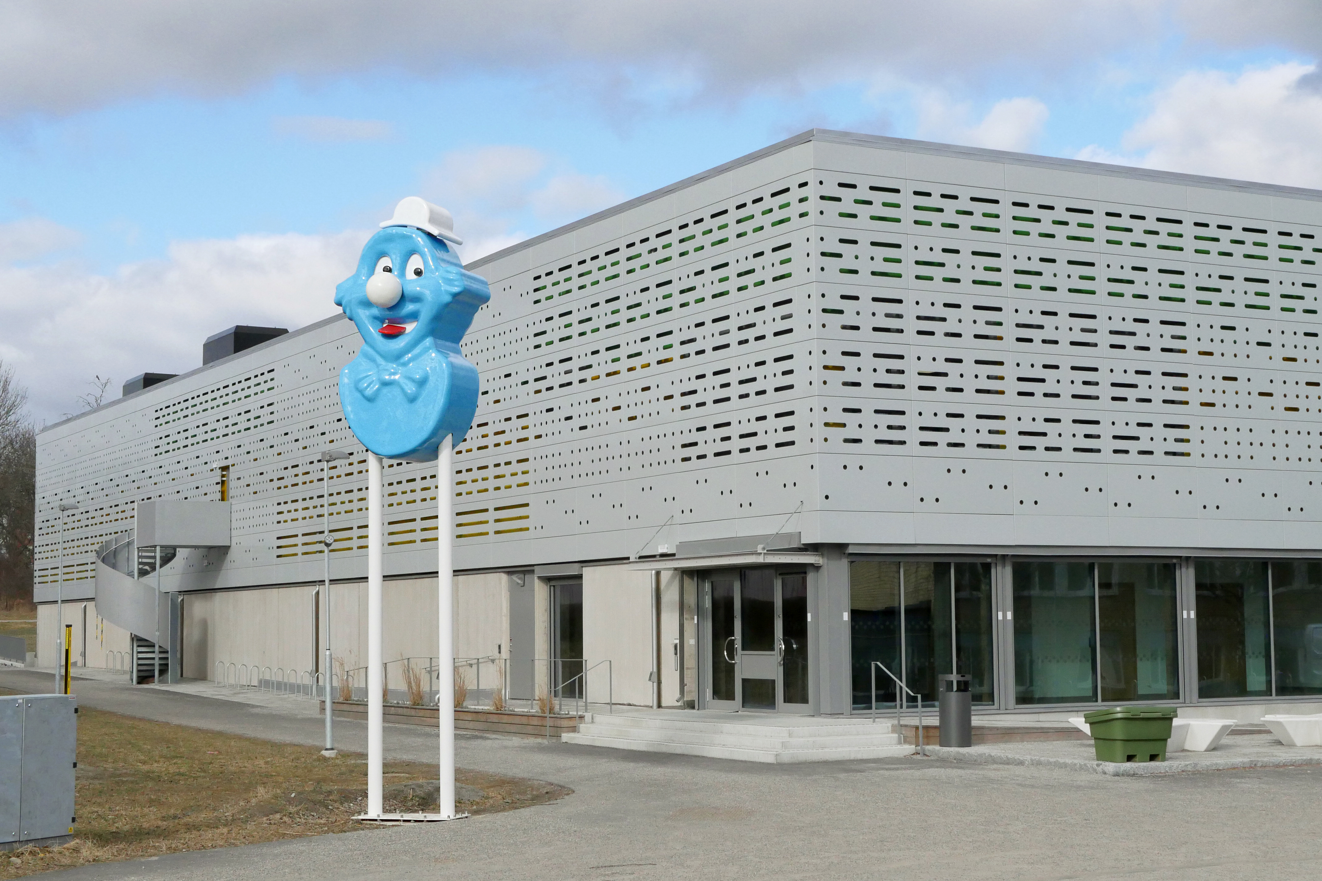 En bild på konstverket Ping Pong i form av en blå figur vars ögon roterar som den kollade på en pingismatch framför nya sporthallen.